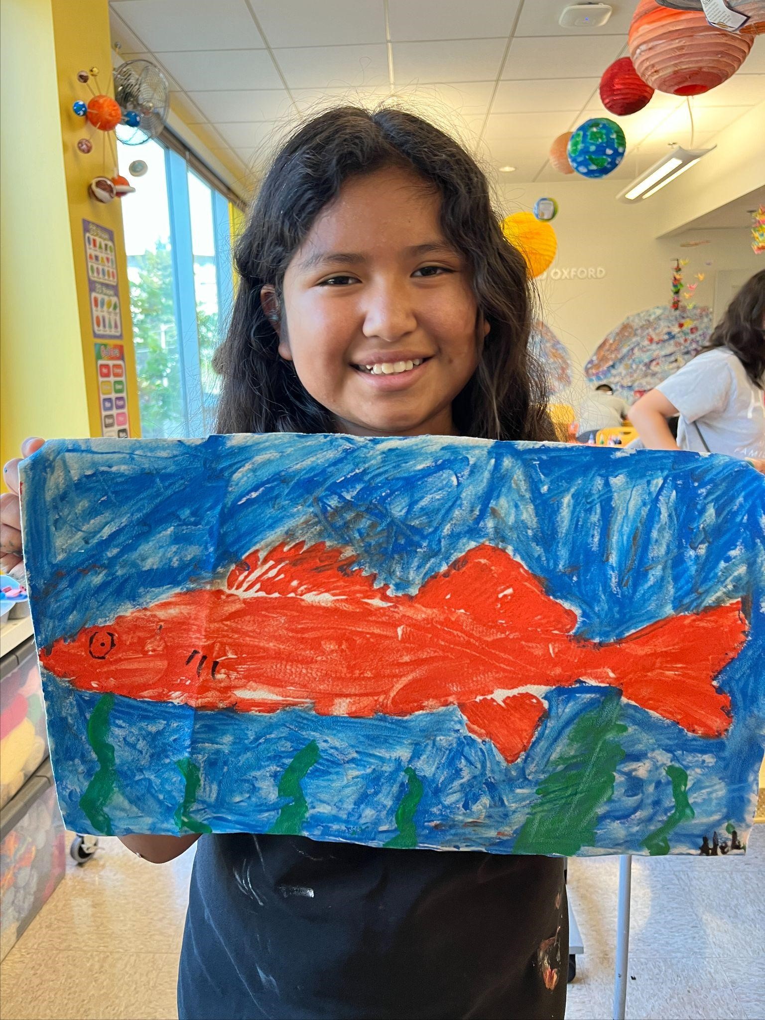 A student shows off her gyotaku print along with a painted ocean background