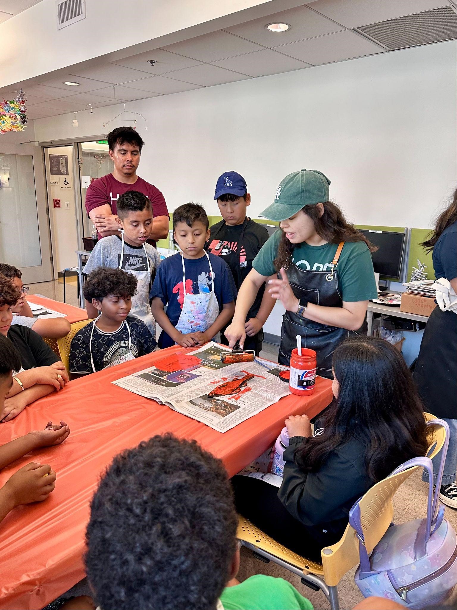 A teacher demonstrates the process of creating a gyotaku using ink, a brayer, and a fish replica