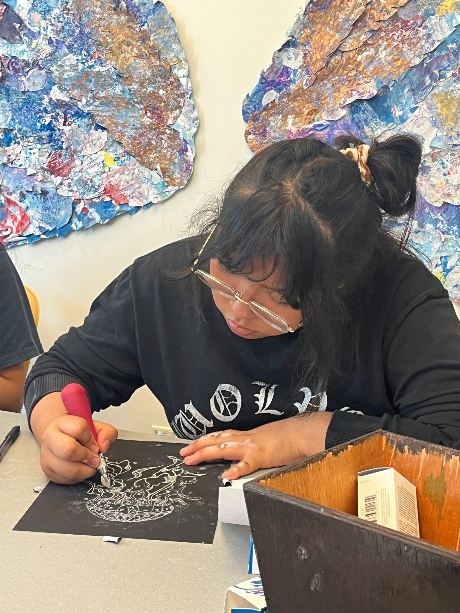 A student etches away at a scratchboard to reveal a jellyfish